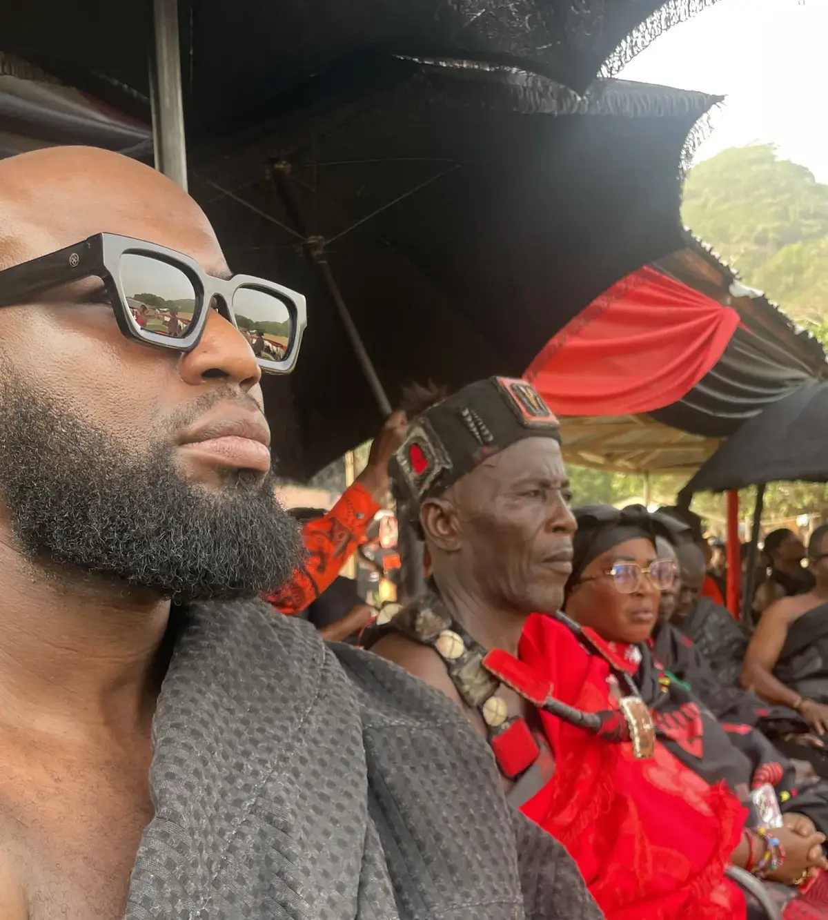 Dennis Toppin tijdens een ceremonie in Ghana, in traditionele kledij te midden van aanwezigen.